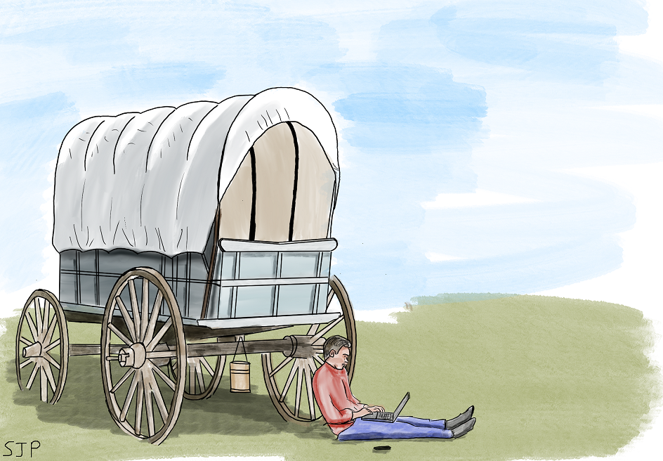 Man sitting with a laptop and phone by a covered wagon